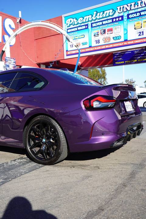 Purple BMW M2 in front of the price board
