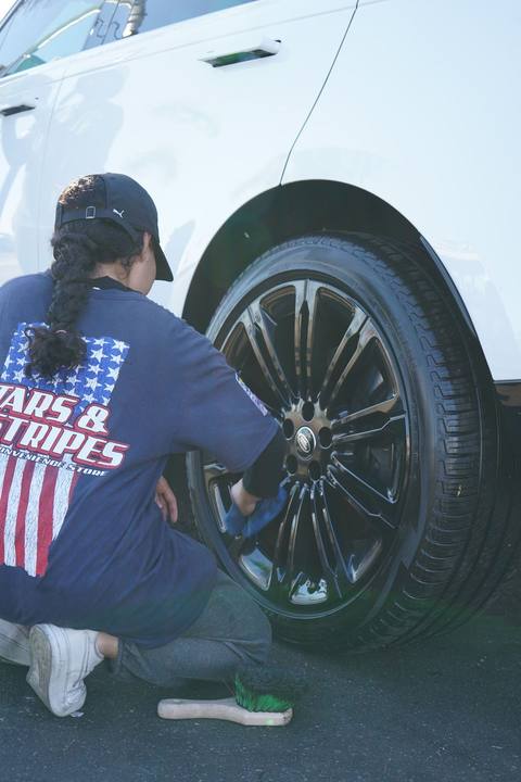 Crew member in a Stars and Stripes shirt dressing the tires