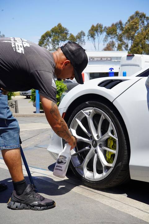 Crew member cleaning the wheels of a white McLaren