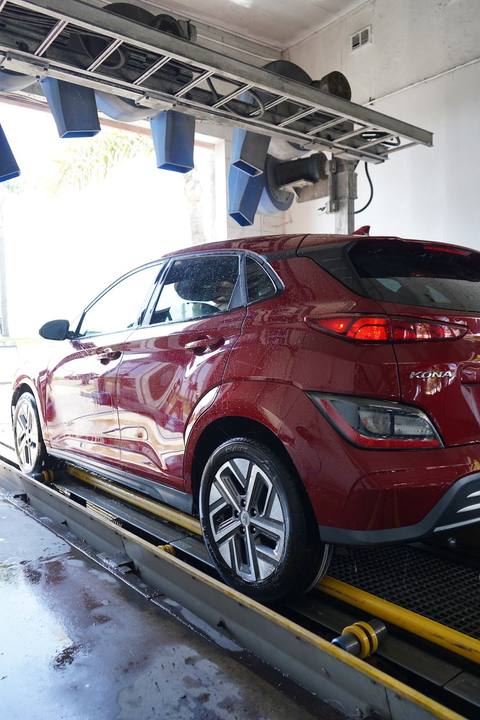 Red Hyundai Kona rolling out of the tunnel, wet and shining