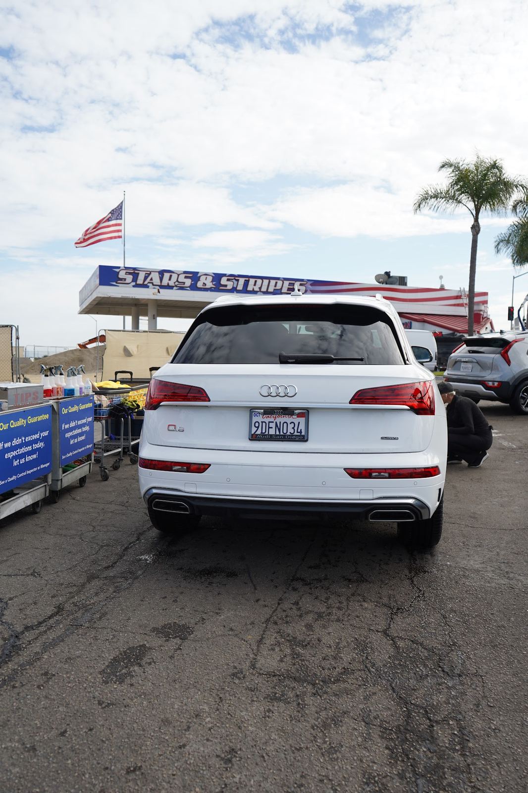 White Audi Q5 parked under the Stars and Stripes sign and flag