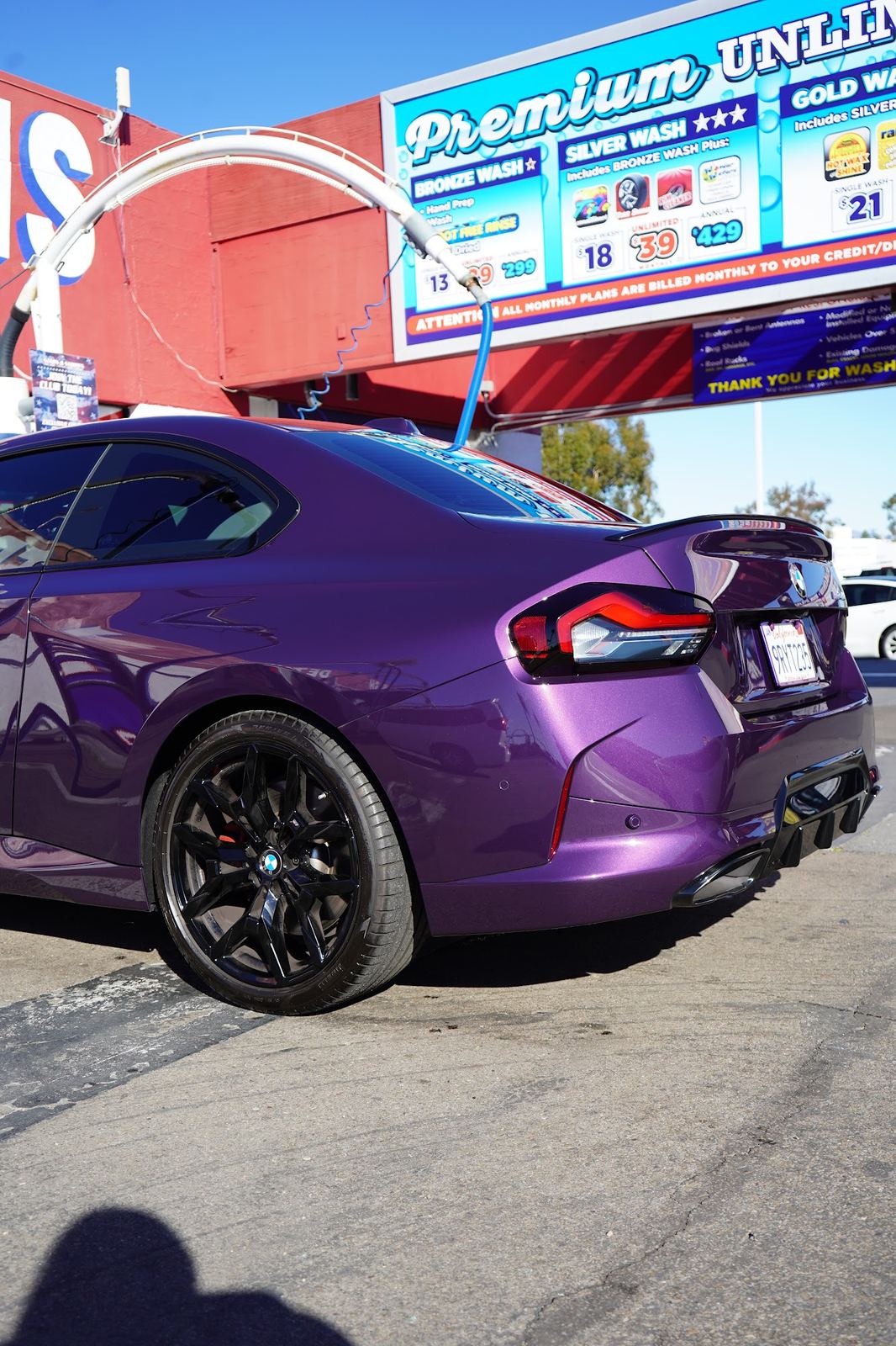 Purple BMW M2 in front of the price board