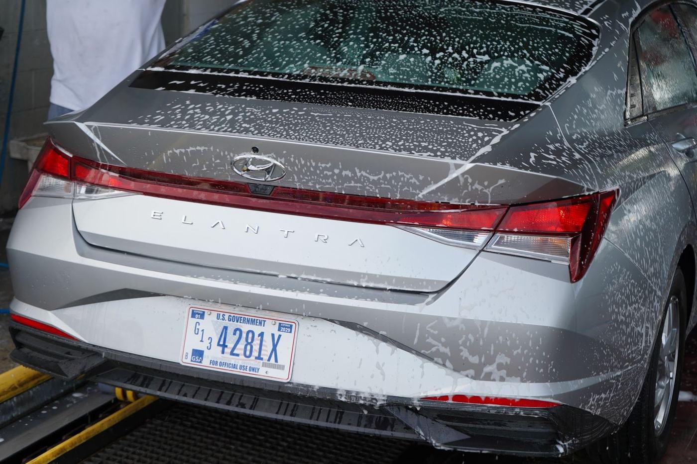 Crew member scrubbing the rear window of a foamed Hyundai Elantra