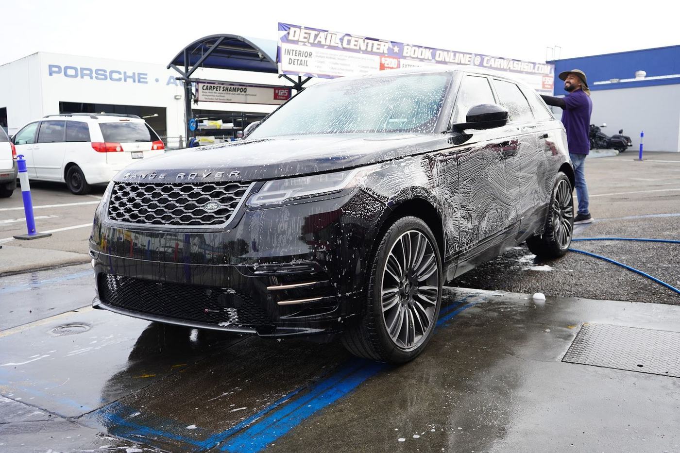 Crew members hand washing a black Range Rover Velar