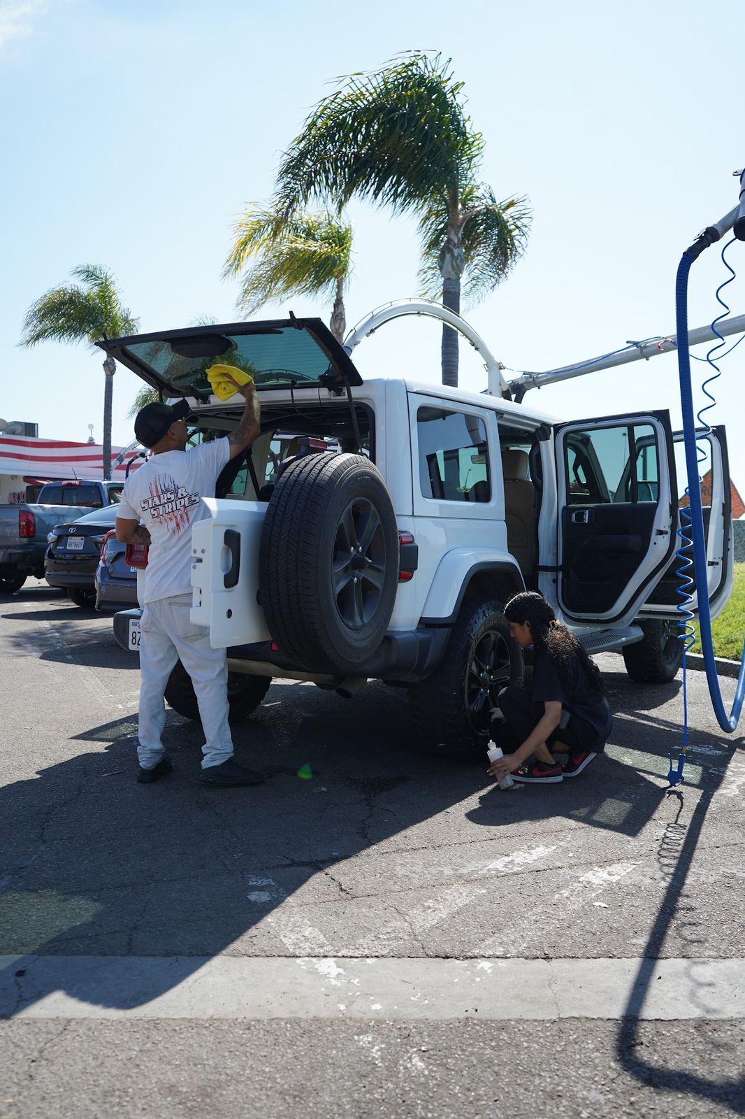 Crew members cleaning a white Jeep Wrangler at the vacuums