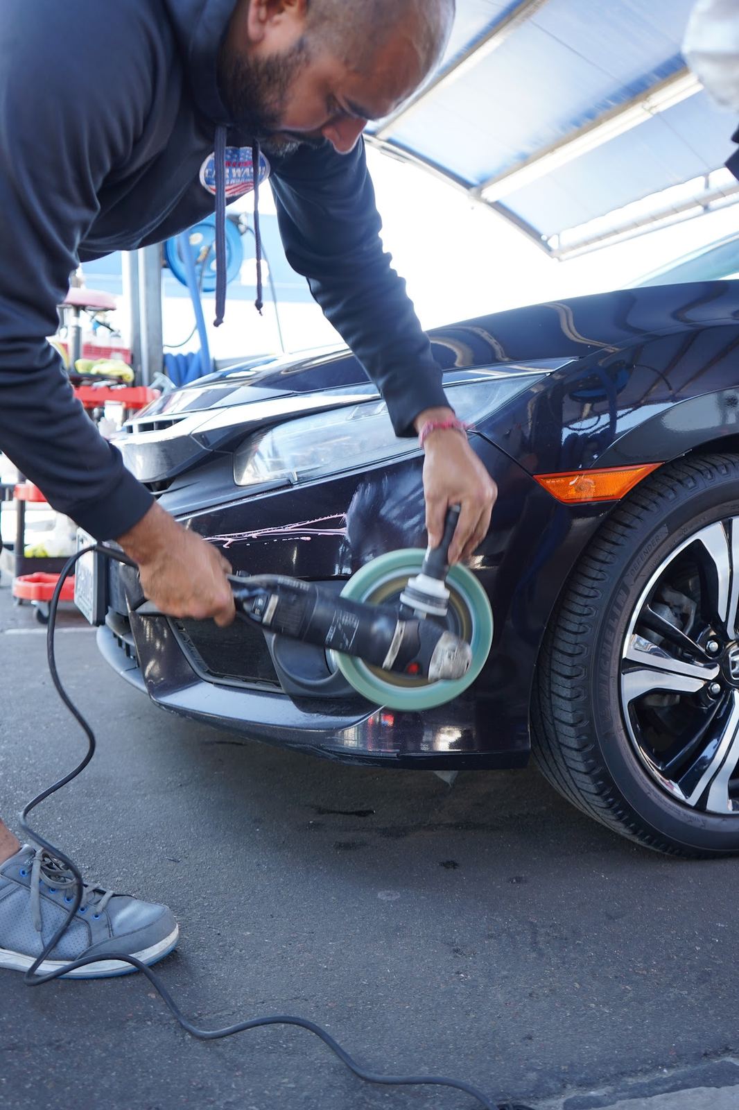 Crew member machine polishing a black Mercedes