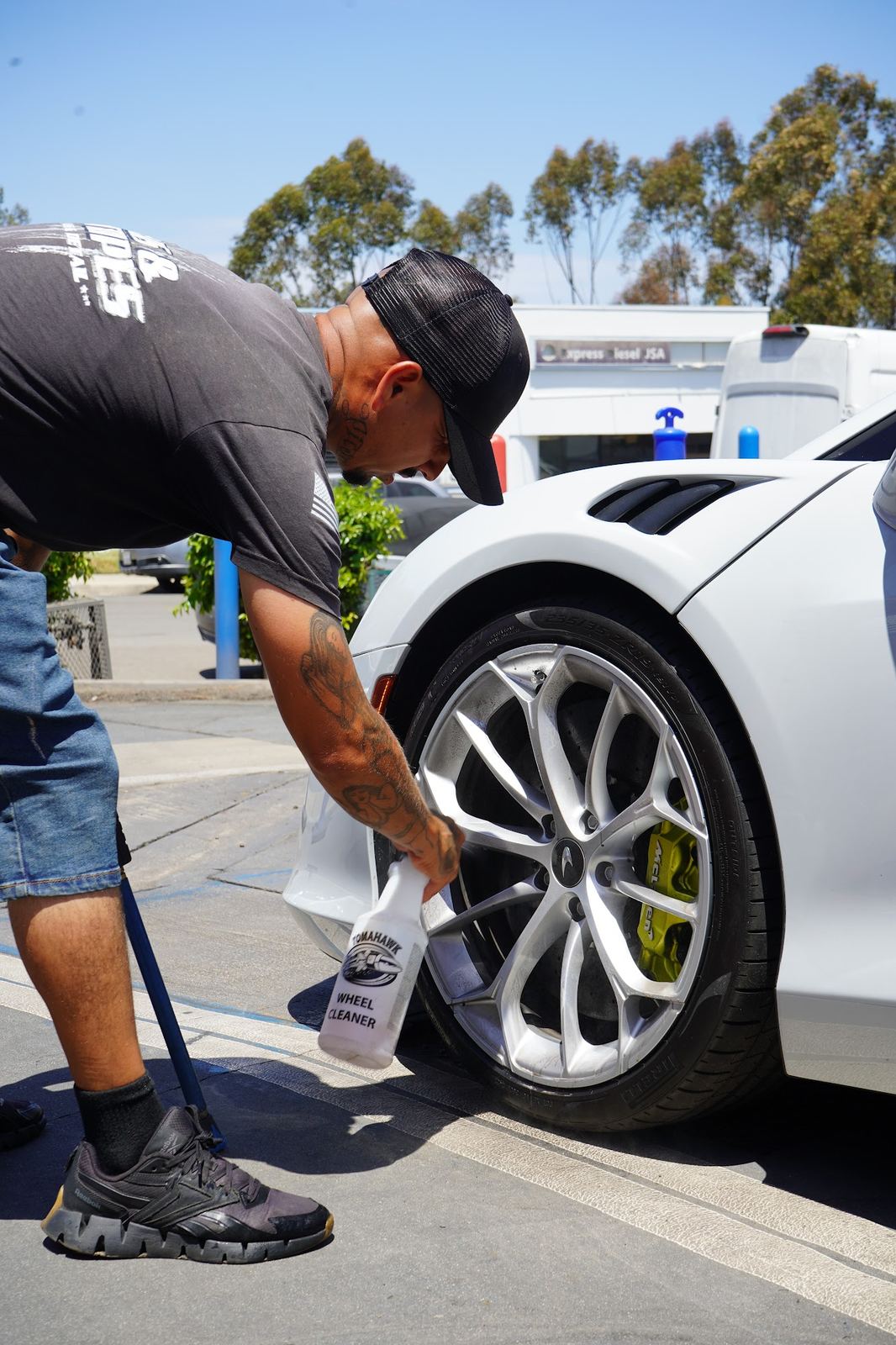 Crew member cleaning the wheels of a white McLaren
