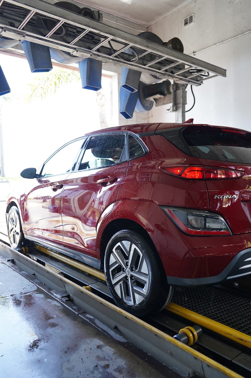 Red Hyundai Kona rolling out of the tunnel, wet and shining