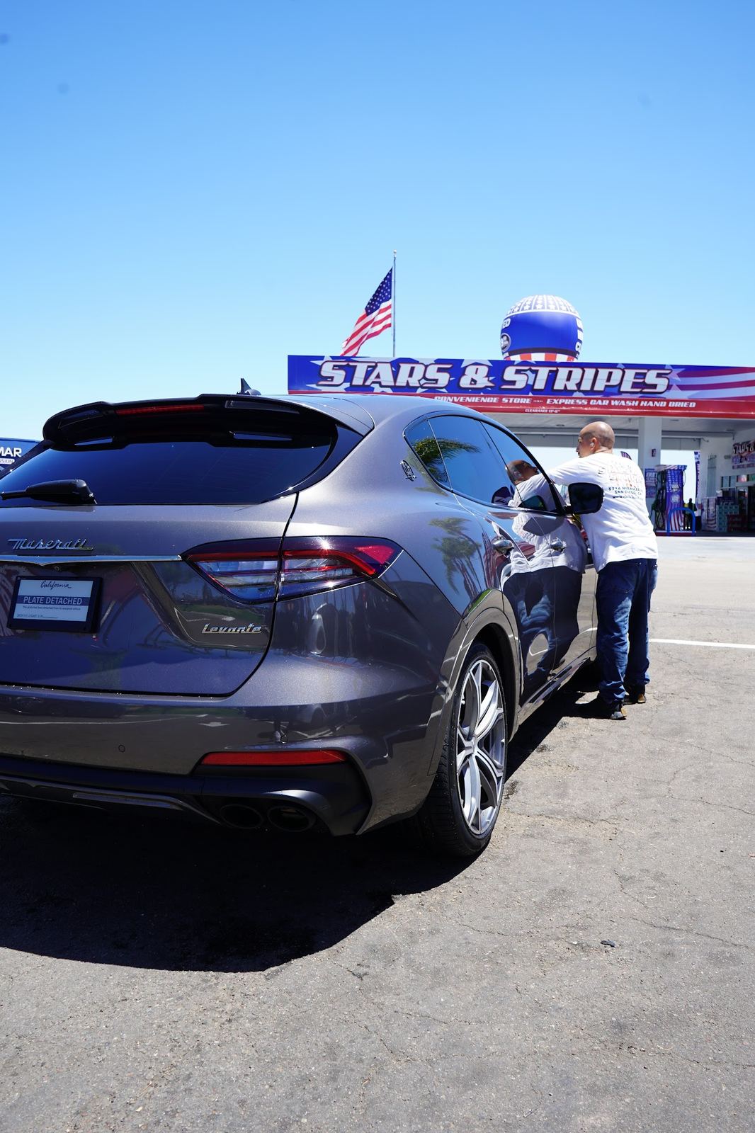 Grey Maserati Levante under the Stars and Stripes sign and flag