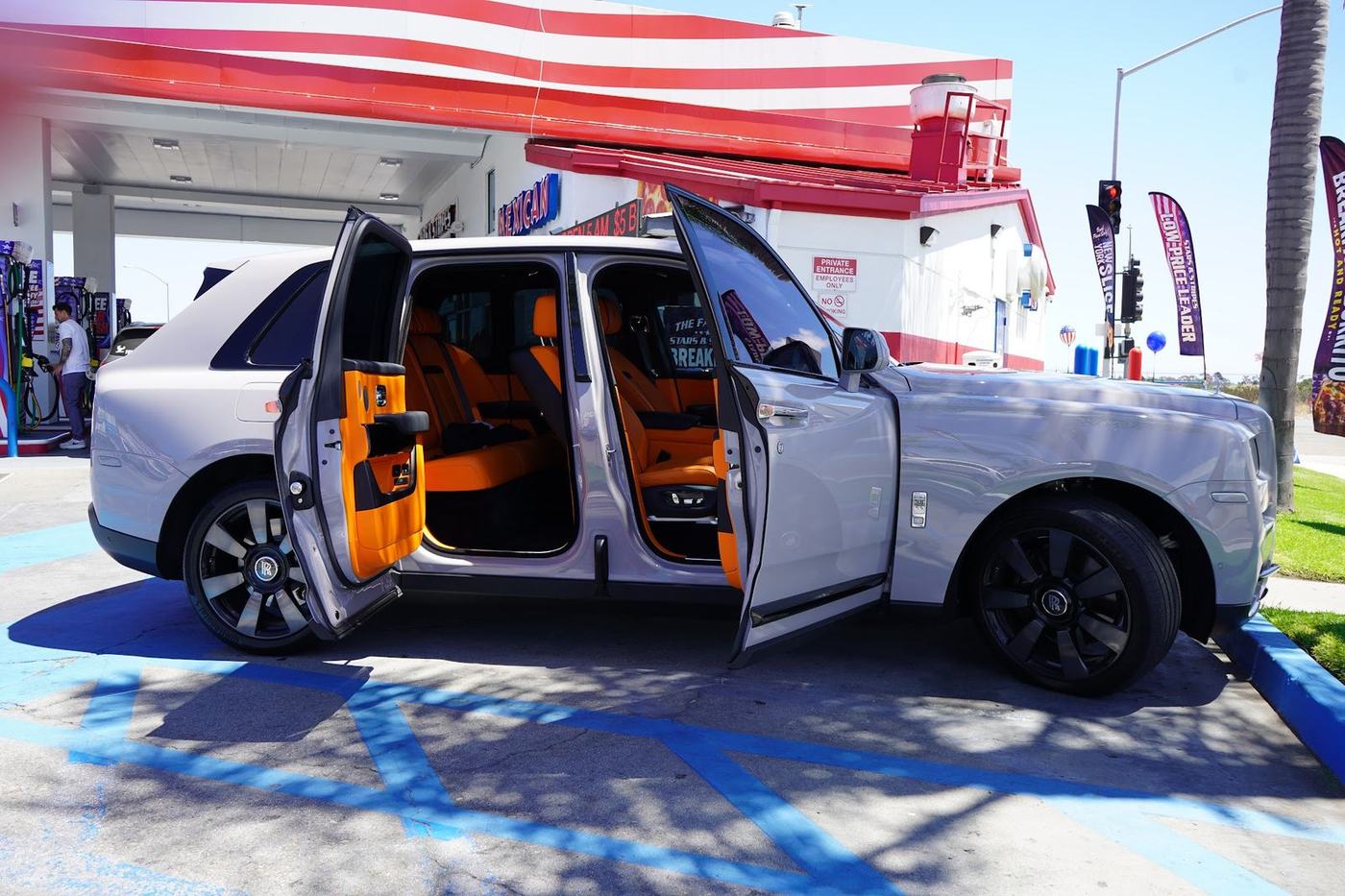 Rolls-Royce Cullinan with all doors open showing the orange leather interior