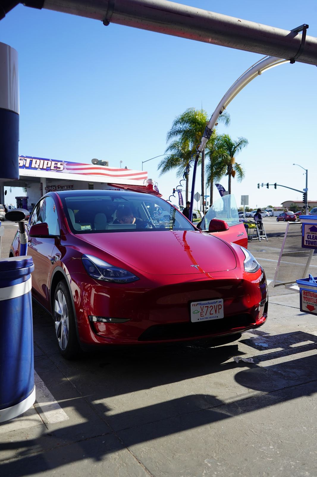 Red Tesla Model Y at the free vacuums under the palm trees